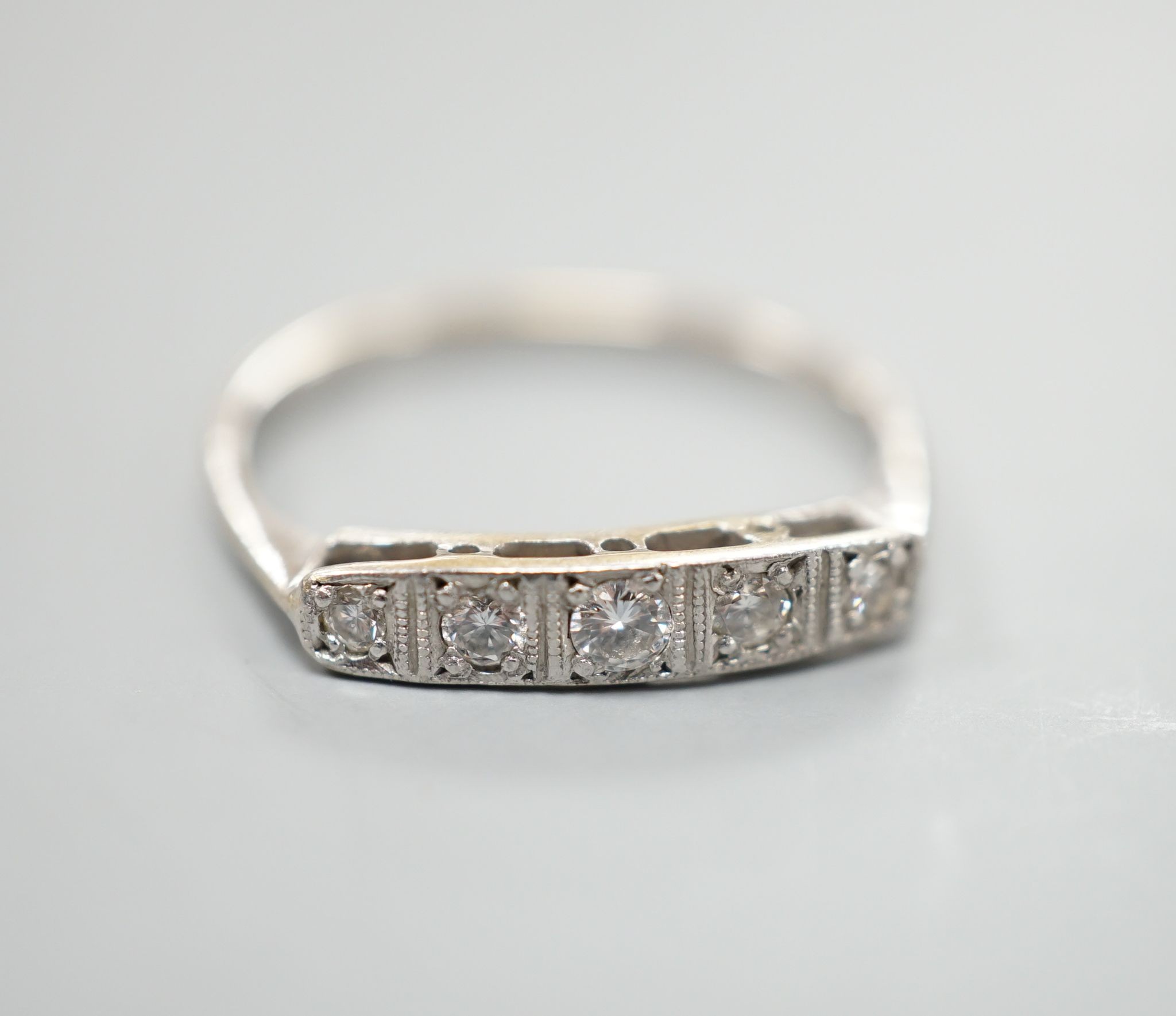 An 18ct and plat, graduated five stone diamond set half hoop ring, size N, gross weight 1.8 grams.